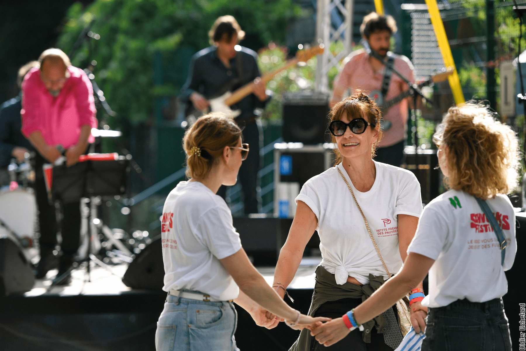 Photo de 3 femmes dansant devant une scène de festival en plein air