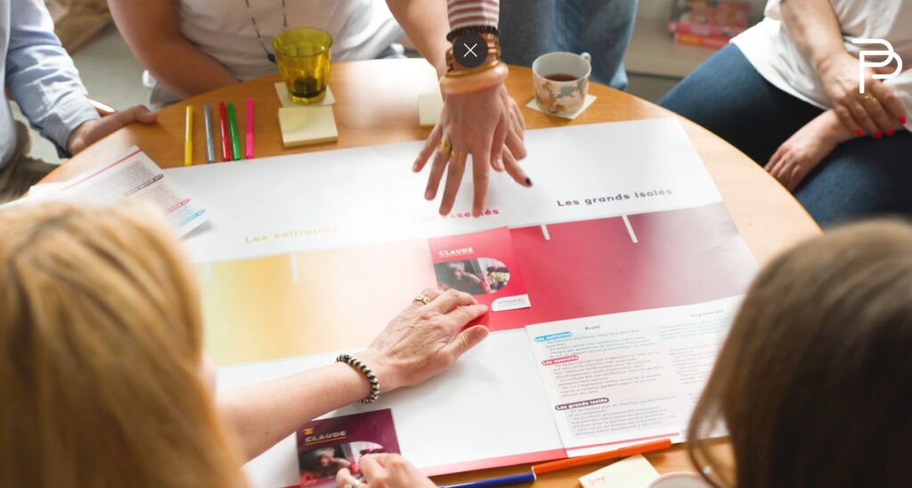 Participants à un atelier Fresque de l'isolement social des Petits Frères des Pauvres, manipulant des cartes en groupe