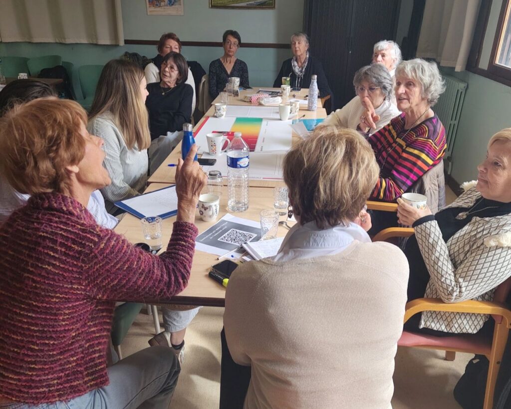 Atelier participatif Fresque de l'isolement social animé par les Petits Frères des Pauvres, participants en discussion autour de cartes