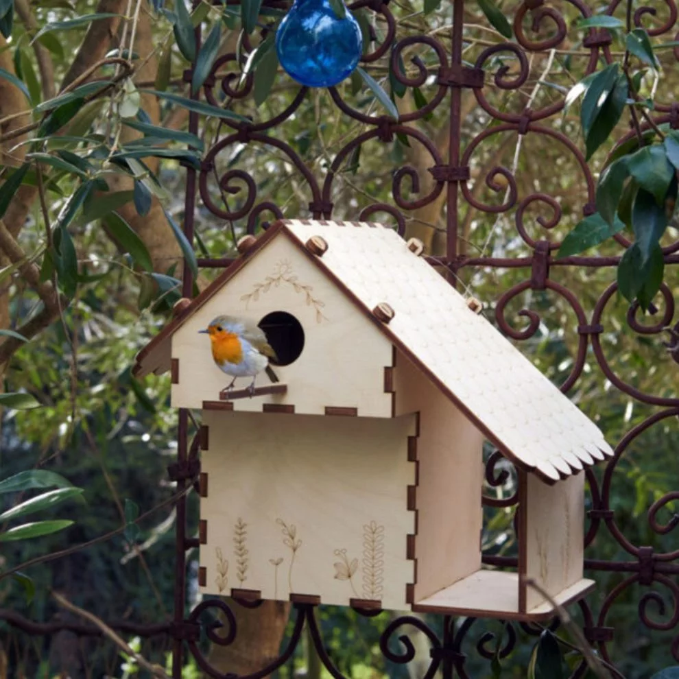 Nichoir en bois suspendu dans un jardin avec un oiseau posé à l’entrée.