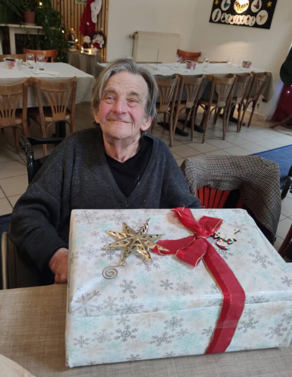 Le sourire de Gérard découvrant ses cadeaux au réveillon des Petits Frères des Pauvres de 2024 - (c) Diane Gilmer